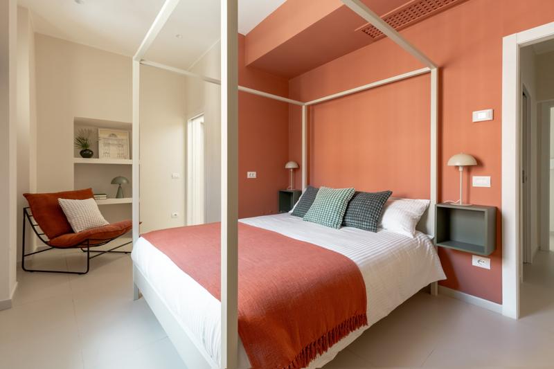 Schlafzimmer mit weißem Himmelbett vor einer korallfarbenen Wand