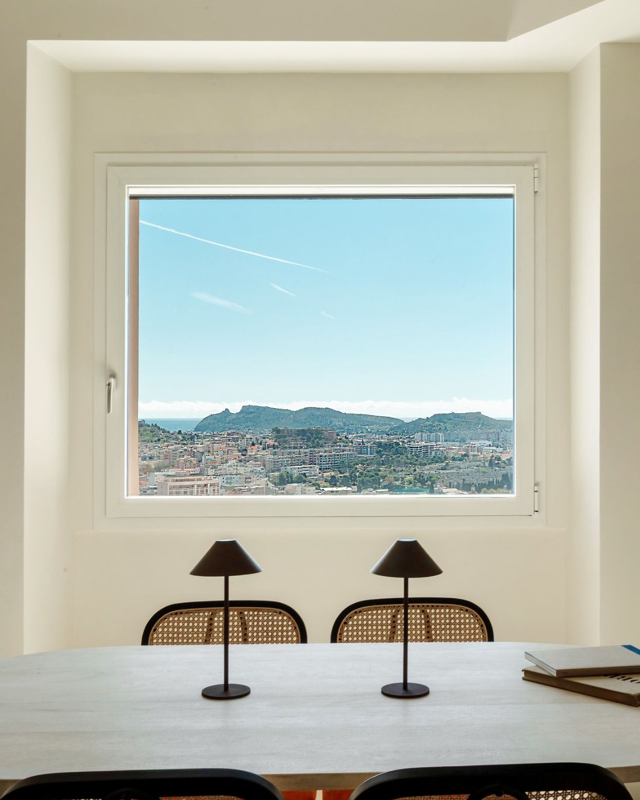Der Esstisch im Tàparas vor einem großen Fenster mit Blick über Cagliari auf die Sella del Diavolo und das Meer